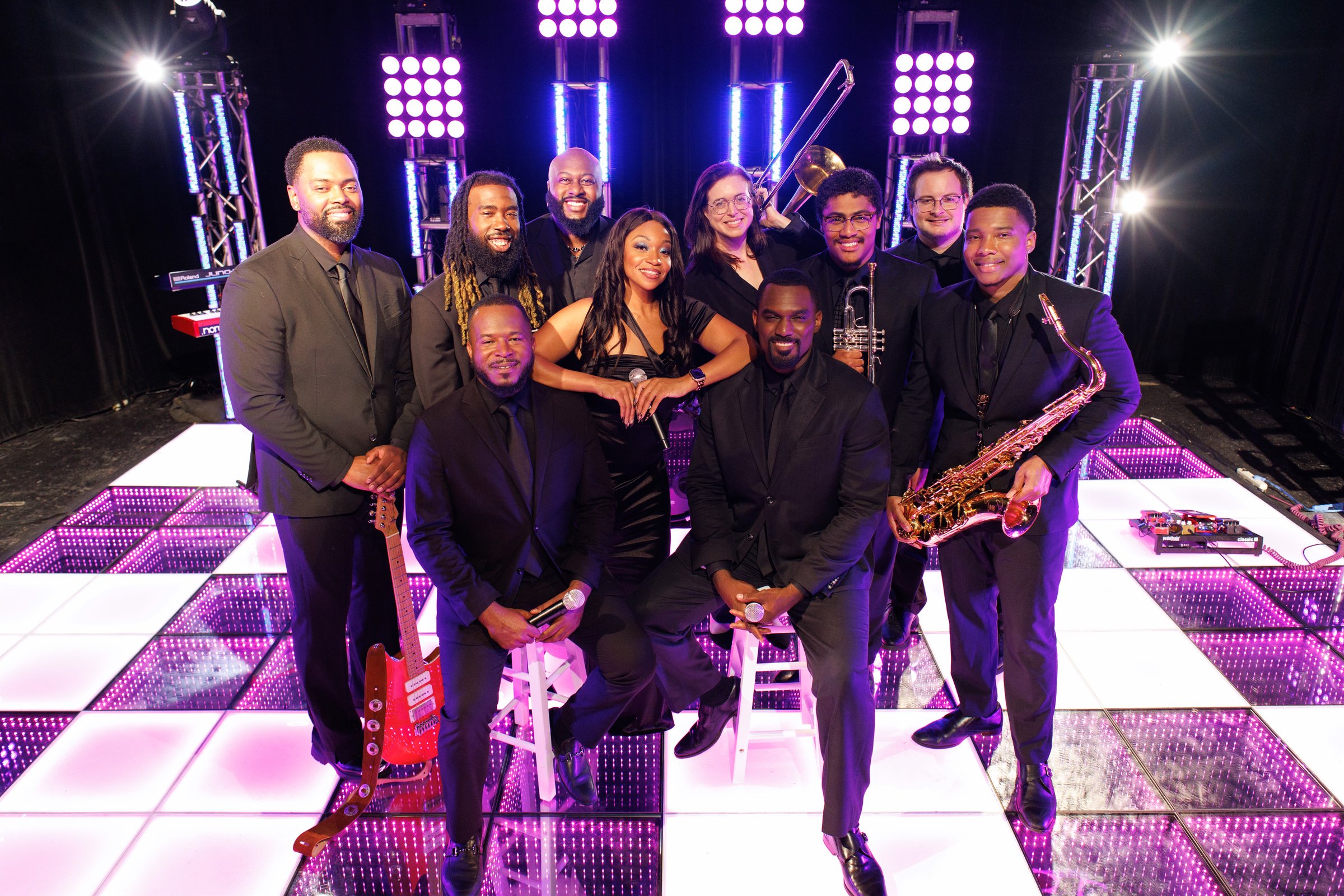 The Wave, a Washington Talent variety band, posing with guitar, trumpet, trombone and saxophone on an illuminated LED dance floor